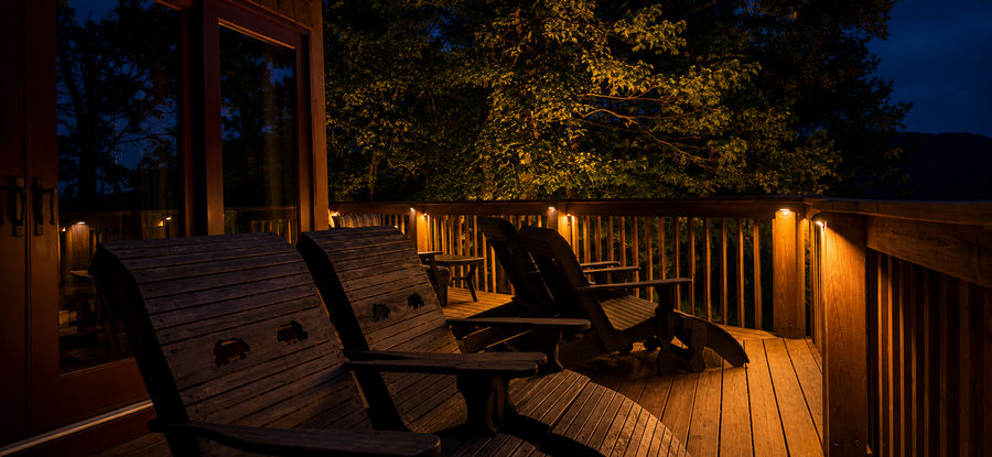 Warm deck railing lights around a covered porch seating area